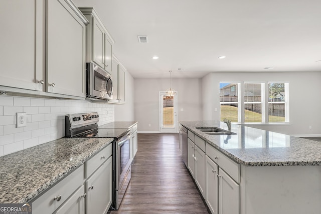 kitchen featuring appliances with stainless steel finishes, baseboards, a sink, dark wood finished floors, and decorative backsplash