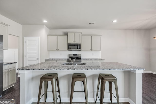 kitchen with dark wood finished floors, visible vents, a breakfast bar, appliances with stainless steel finishes, and a sink