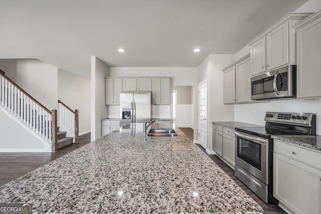 kitchen with tasteful backsplash, baseboards, a sink, appliances with stainless steel finishes, and light stone countertops