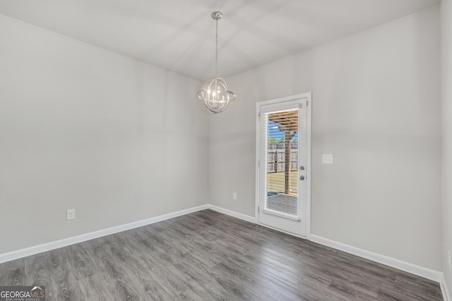 unfurnished room with a chandelier, dark wood-style flooring, and baseboards