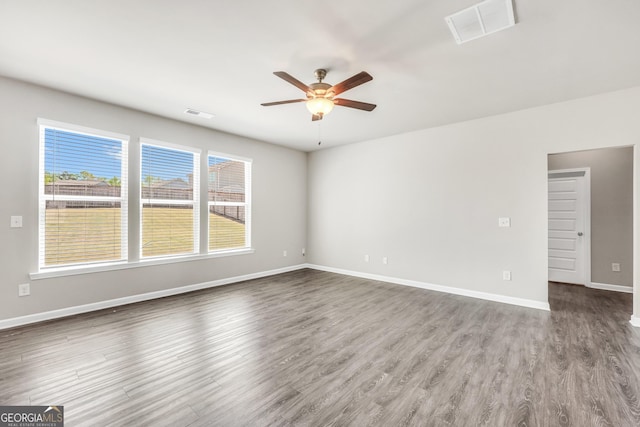 spare room with wood finished floors, ceiling fan, baseboards, and visible vents