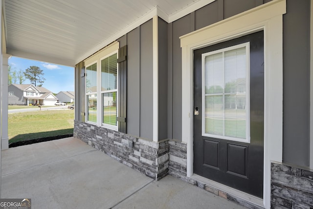 entrance to property featuring board and batten siding, stone siding, and covered porch