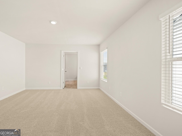 unfurnished room featuring baseboards and light carpet