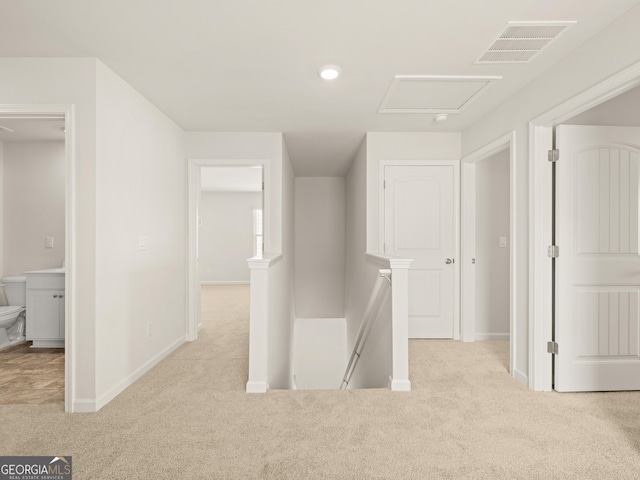corridor with visible vents, baseboards, an upstairs landing, and carpet floors