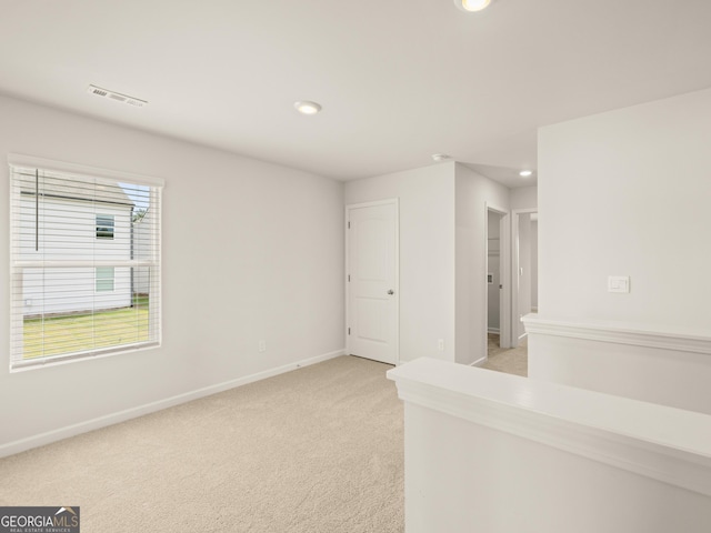 empty room featuring light carpet, recessed lighting, visible vents, and baseboards