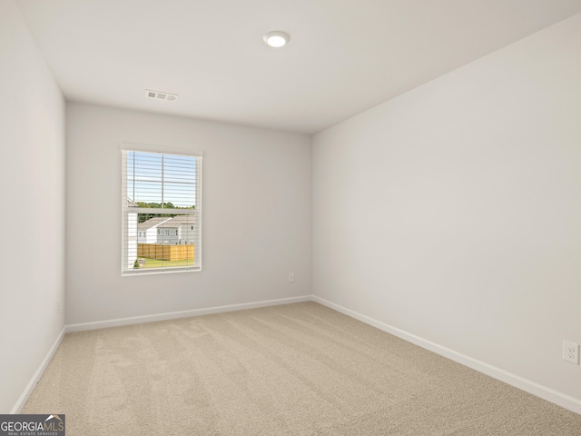 empty room featuring visible vents, light colored carpet, and baseboards