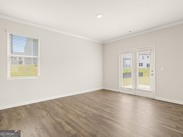 spare room with ornamental molding, baseboards, visible vents, and dark wood-style floors