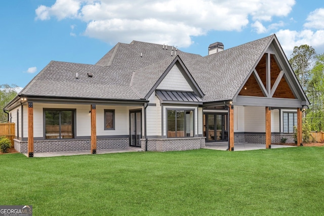 back of property with roof with shingles, a yard, a patio, and a chimney