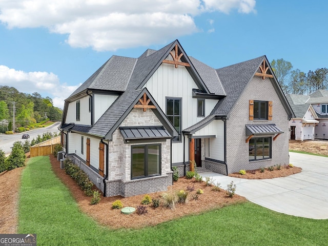 modern farmhouse with roof with shingles, driveway, board and batten siding, stone siding, and a front yard