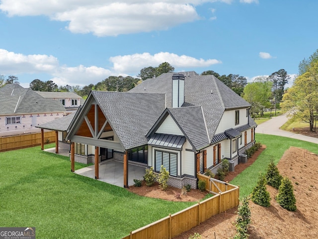 rear view of property with a patio area, a yard, metal roof, fence, and a standing seam roof