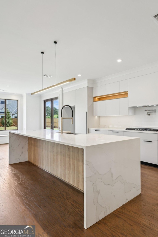 kitchen featuring white cabinets, dark wood-type flooring, modern cabinets, a spacious island, and a sink