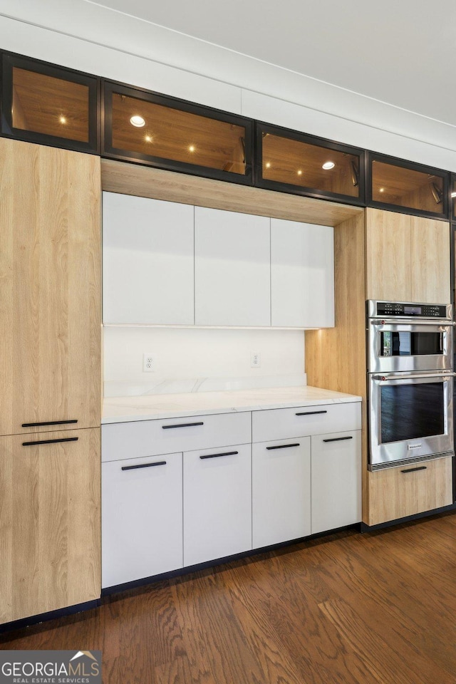 kitchen with modern cabinets, light countertops, white cabinetry, dark wood-type flooring, and stainless steel double oven