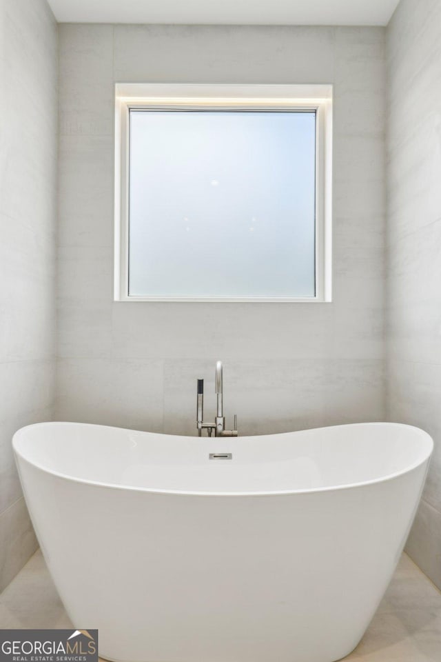 full bath featuring a freestanding bath and a healthy amount of sunlight