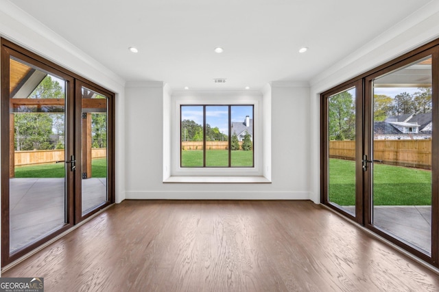 interior space with visible vents, baseboards, ornamental molding, and wood finished floors