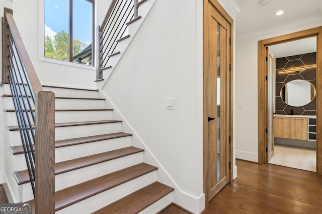 staircase with wood finished floors, baseboards, and recessed lighting