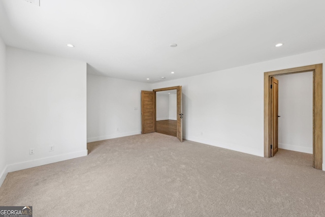 spare room with recessed lighting, light colored carpet, and baseboards