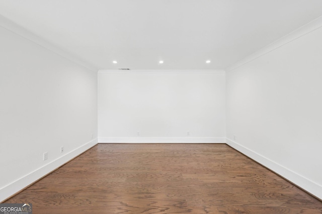 spare room with ornamental molding, baseboards, wood finished floors, and visible vents