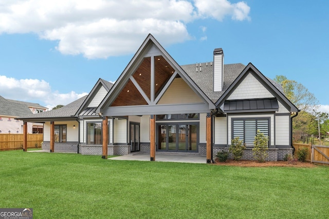 rear view of property with a standing seam roof, a yard, fence, and a chimney