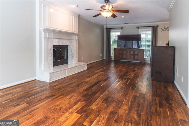unfurnished living room featuring crown molding, a high end fireplace, ceiling fan, baseboards, and dark wood-style flooring