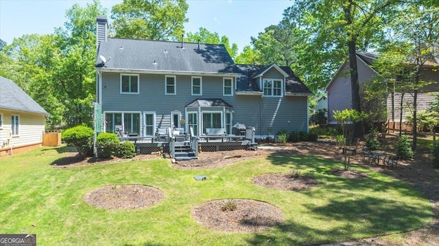 rear view of property featuring a wooden deck, a lawn, and a chimney