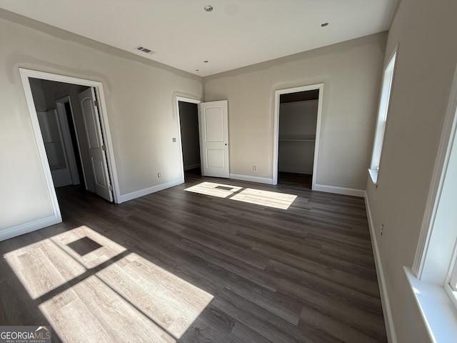 unfurnished bedroom with baseboards, visible vents, a closet, and dark wood-type flooring
