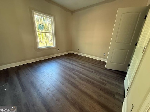 spare room featuring baseboards and dark wood-style flooring