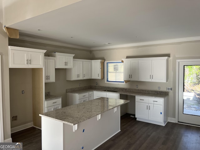 kitchen featuring light stone countertops, crown molding, a kitchen island, white cabinetry, and dark wood finished floors
