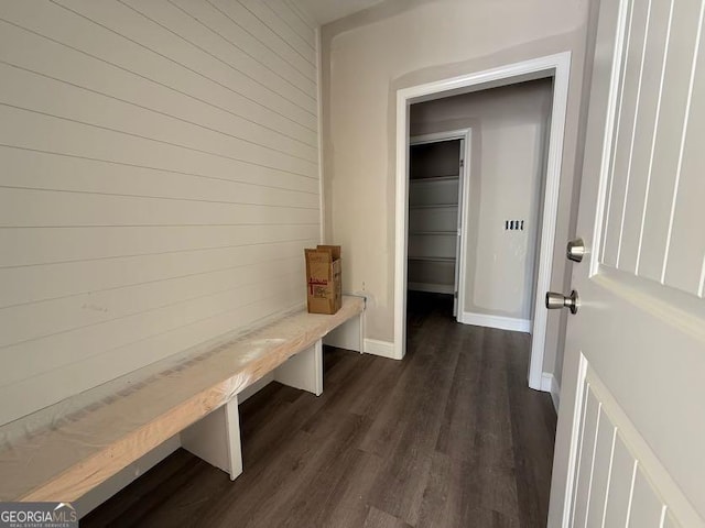mudroom featuring dark wood-type flooring, wooden walls, and baseboards