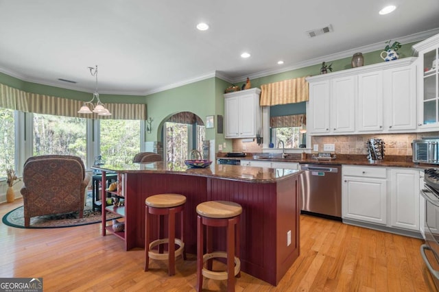 kitchen featuring a center island, stainless steel dishwasher, white cabinets, and plenty of natural light