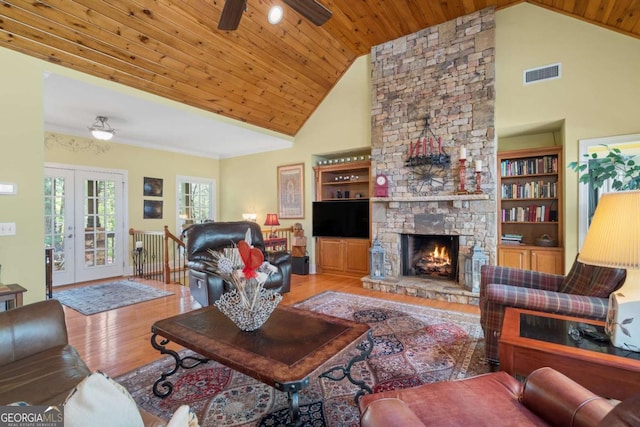 living room with a stone fireplace, french doors, visible vents, high vaulted ceiling, and wood finished floors