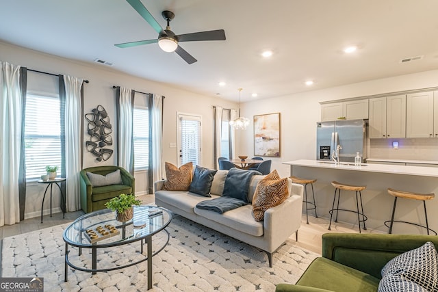 living room featuring recessed lighting, light wood finished floors, visible vents, and ceiling fan with notable chandelier