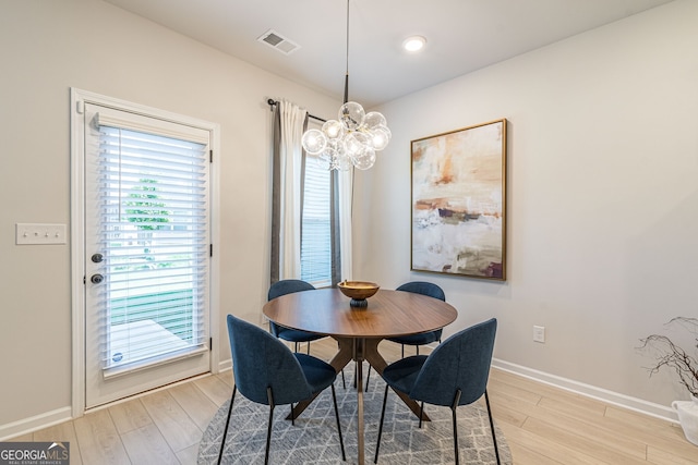dining area featuring a chandelier, visible vents, baseboards, and light wood-style flooring