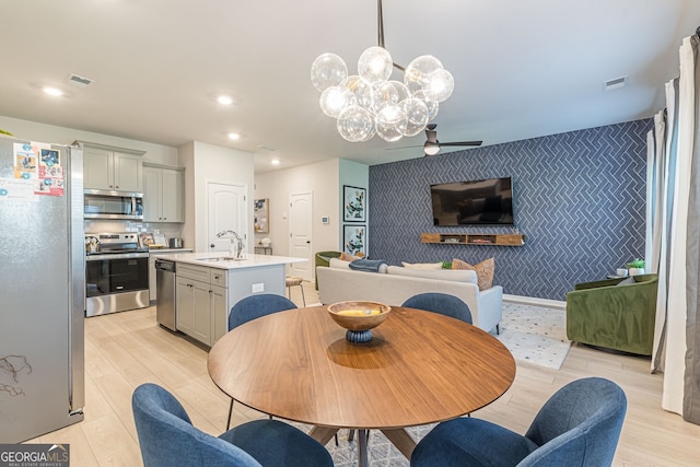 dining space with visible vents, ceiling fan with notable chandelier, an accent wall, and wallpapered walls