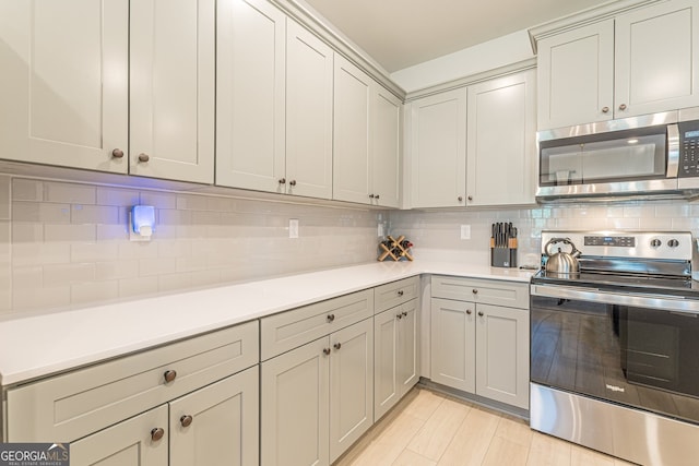 kitchen with light countertops, decorative backsplash, and appliances with stainless steel finishes