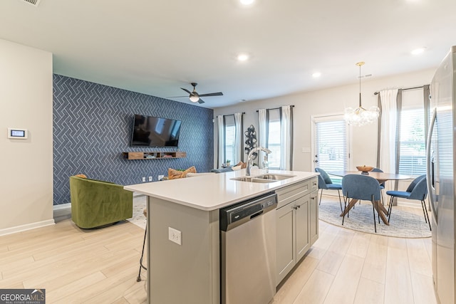 kitchen featuring baseboards, wallpapered walls, an accent wall, appliances with stainless steel finishes, and a sink