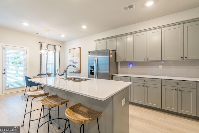 kitchen with a sink, stainless steel fridge with ice dispenser, gray cabinetry, and visible vents