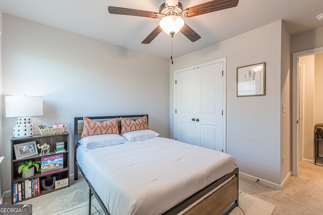bedroom with light carpet, baseboards, a closet, and a ceiling fan