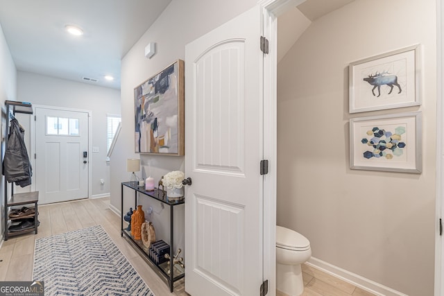 foyer featuring light wood finished floors, baseboards, visible vents, and recessed lighting