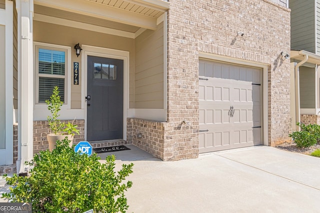 doorway to property featuring brick siding and driveway