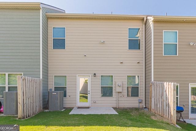 rear view of house with central AC, fence, a lawn, and a patio area