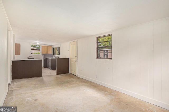 unfurnished living room with baseboards, plenty of natural light, and unfinished concrete floors