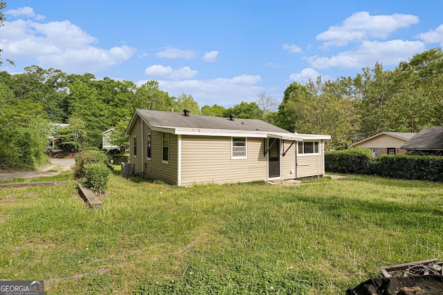 rear view of house featuring central AC and a lawn
