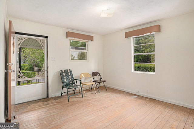 living area with ornamental molding, light wood-style flooring, plenty of natural light, and baseboards
