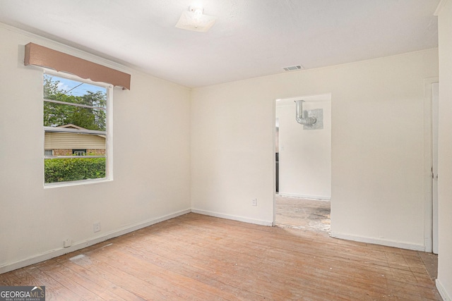 empty room with light wood-type flooring, baseboards, and visible vents