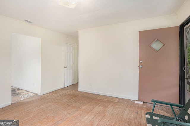 unfurnished room featuring baseboards, visible vents, and hardwood / wood-style flooring