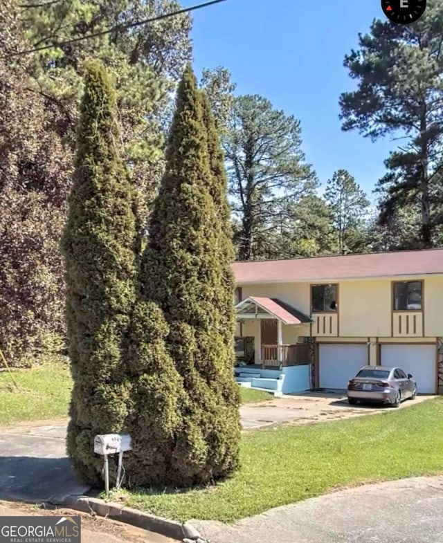 view of front of home with concrete driveway, stucco siding, a garage, and a front lawn