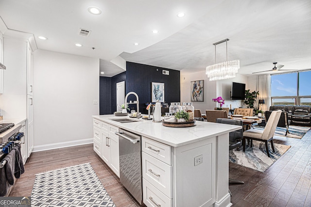 kitchen featuring an island with sink, wood finished floors, visible vents, a sink, and ceiling fan with notable chandelier