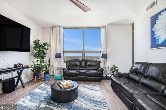 living room featuring expansive windows, a ceiling fan, wood finished floors, and visible vents