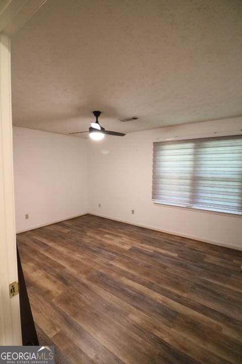 spare room with dark wood-type flooring and a ceiling fan