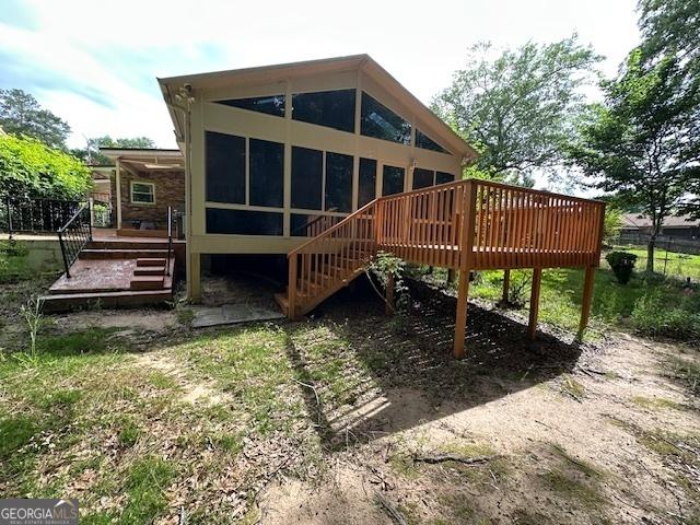 rear view of property with a deck, stairs, and a sunroom